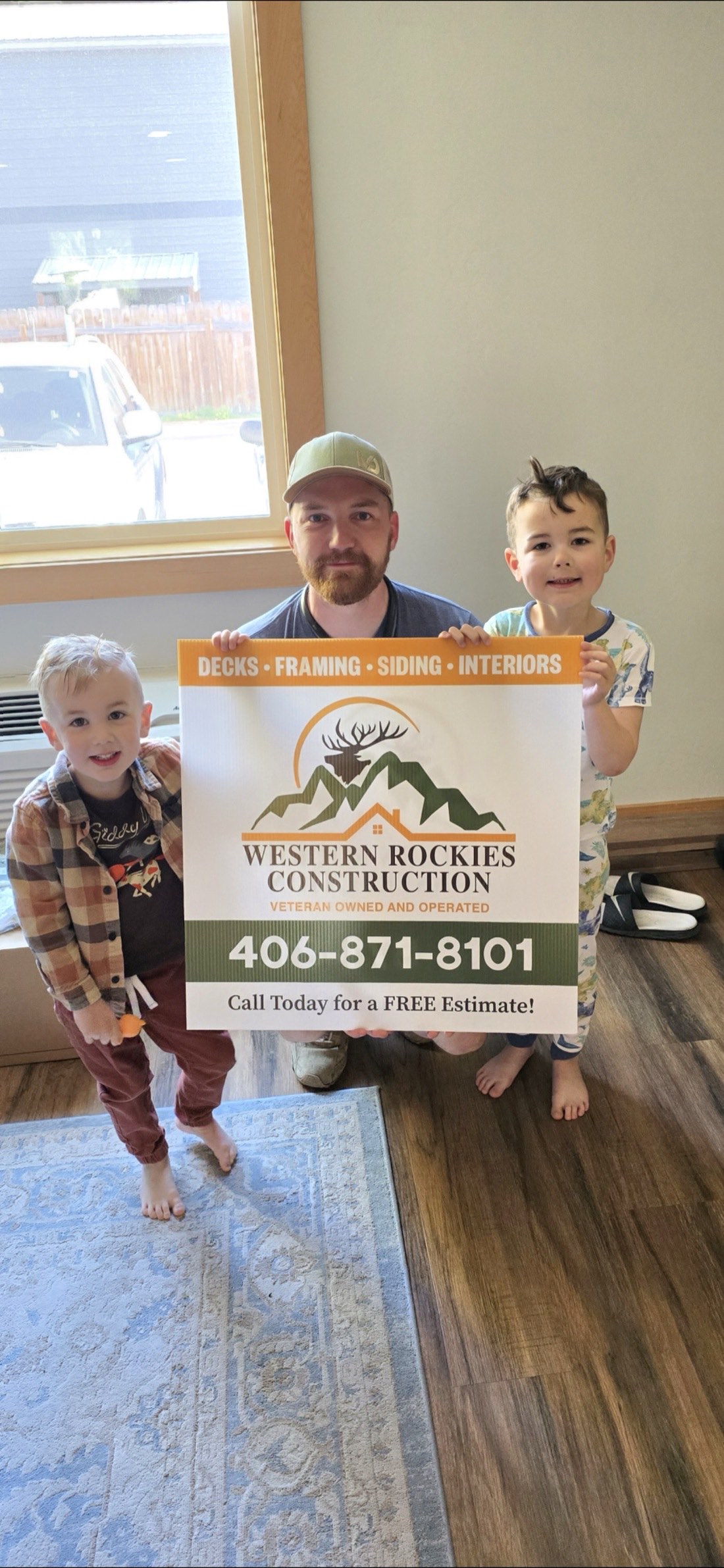 Josiah Walker of Western Rockies Construction with his sons holding the veteran-owned company sign